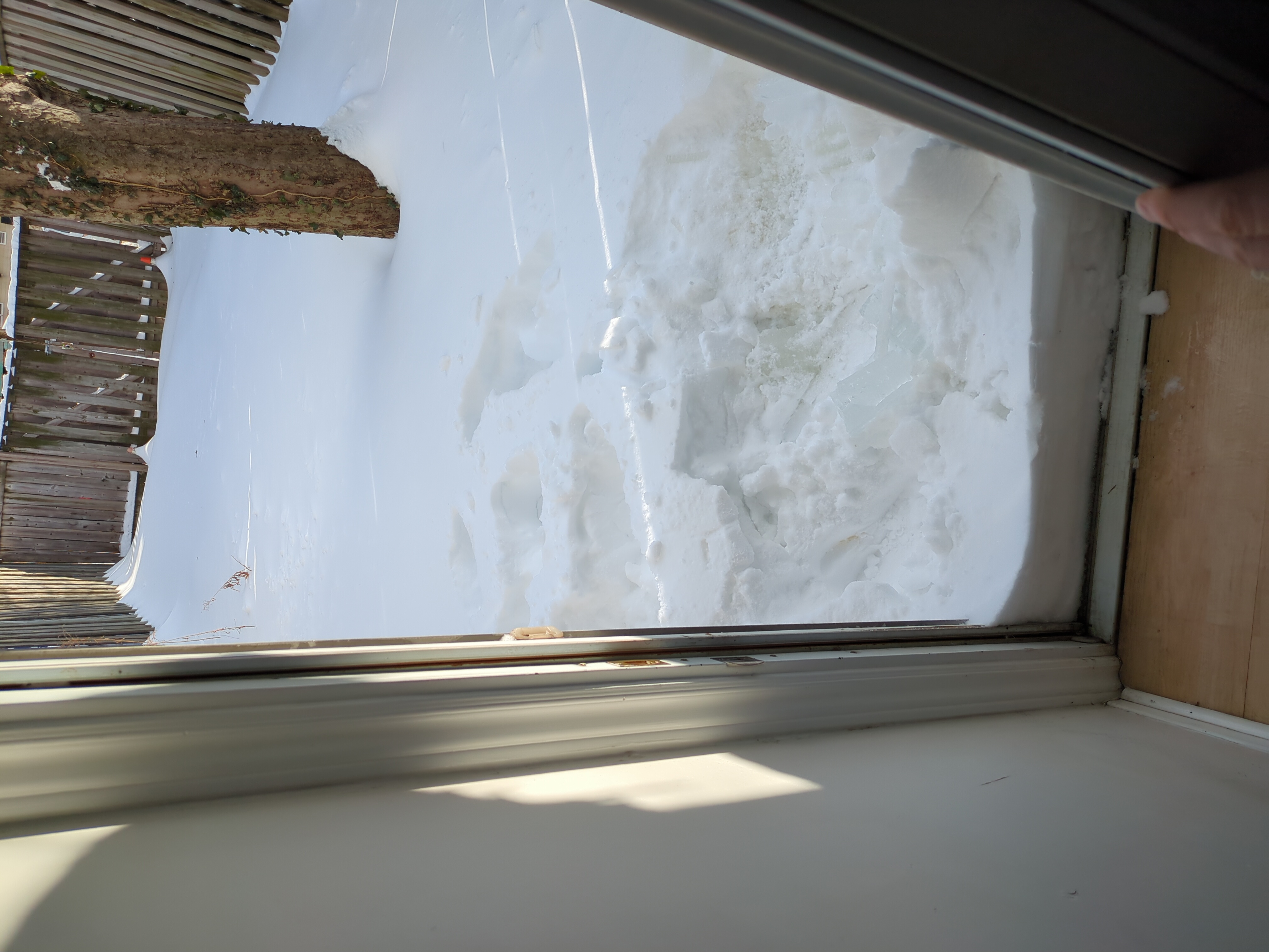 An open door revealing snow packed neatly against where the door rests when closed.