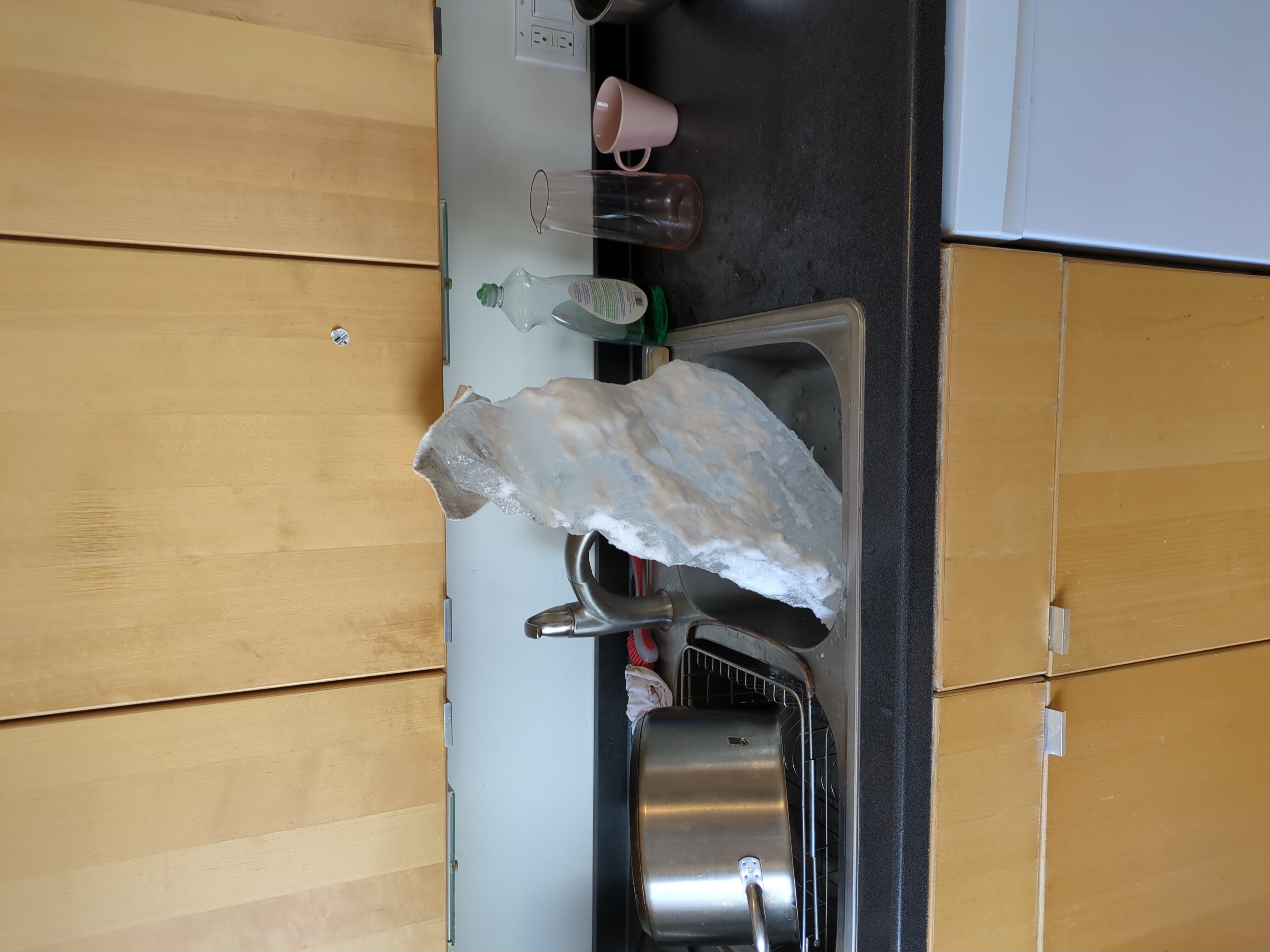 Another view of the large, irregular block of ice in a kitchen sink.